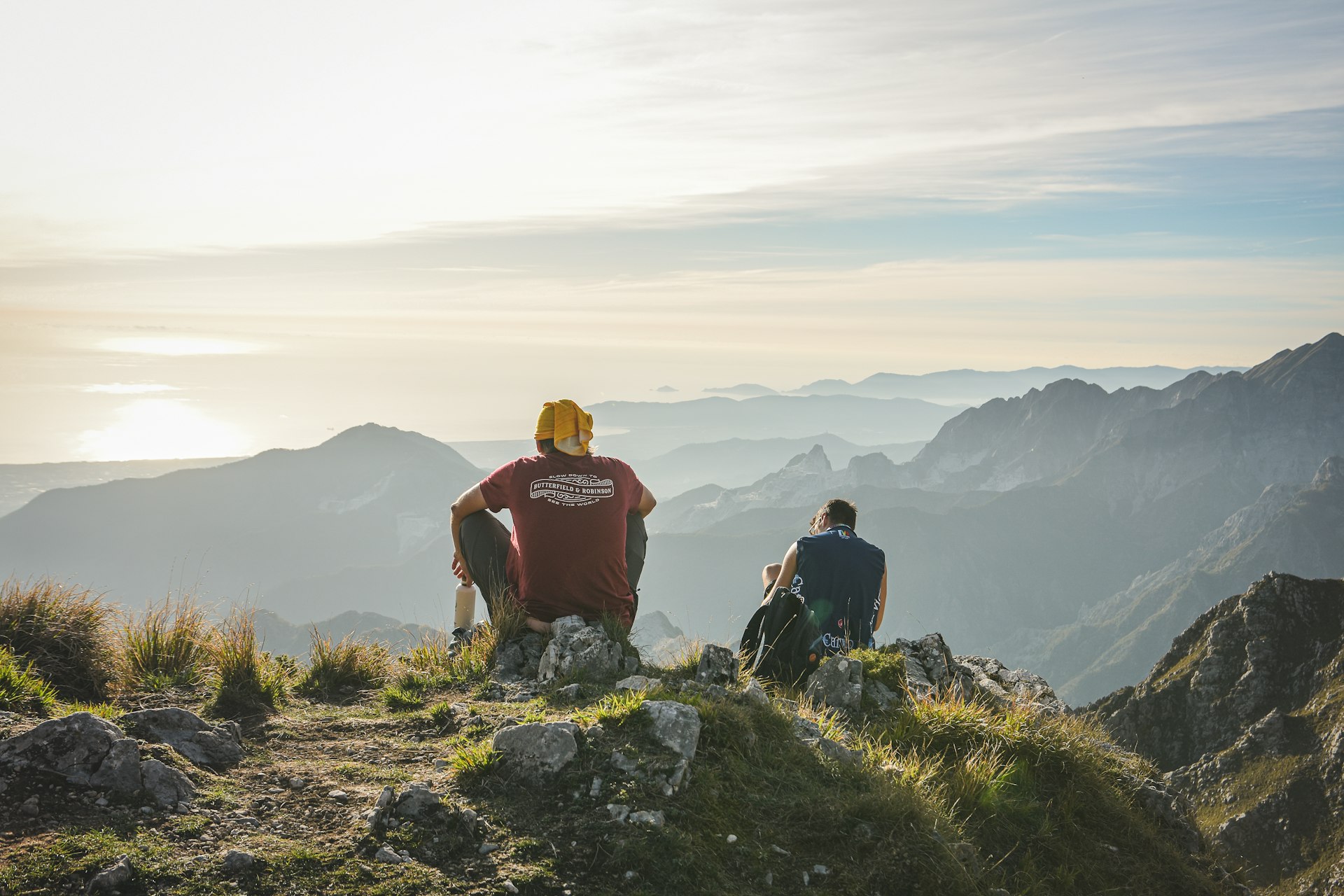 Two hikers stop to look out over the view in a hilly region on a sunny day