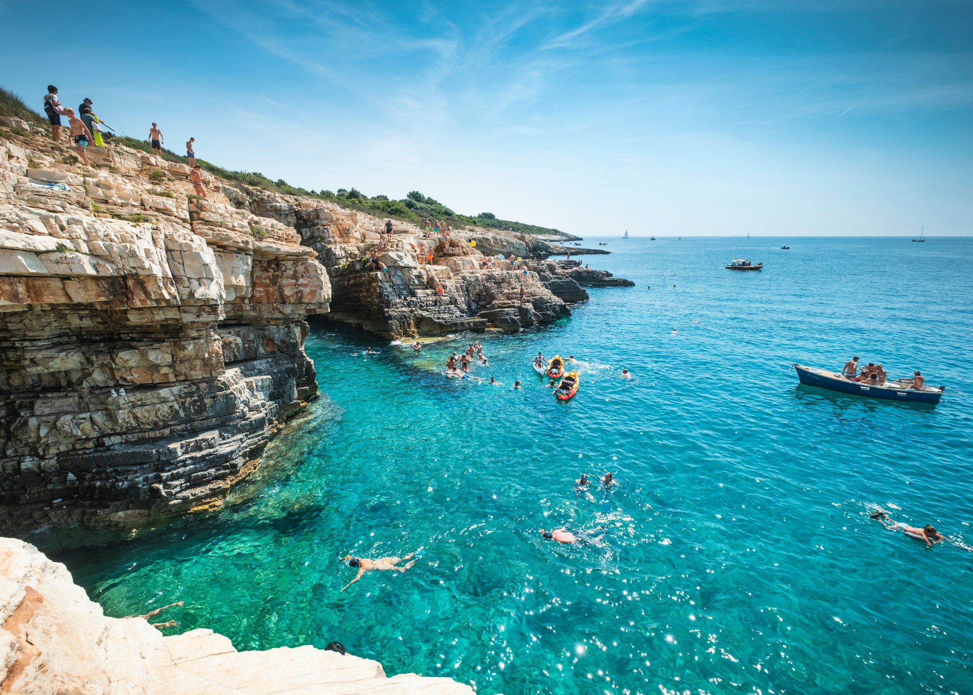 Boys dive into the sea from a cliff in Premantura, Croatia, Europe