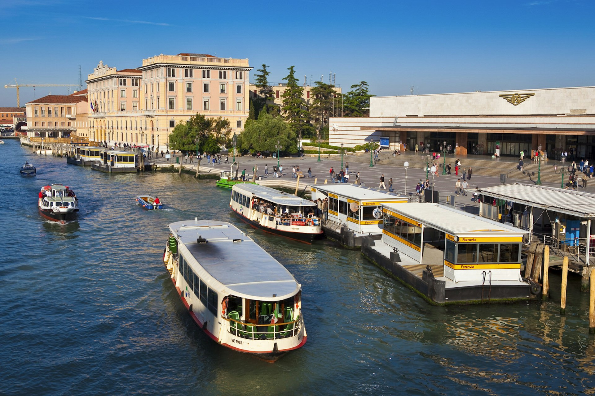 Canal boats depart from a stop outside a train station in Venice