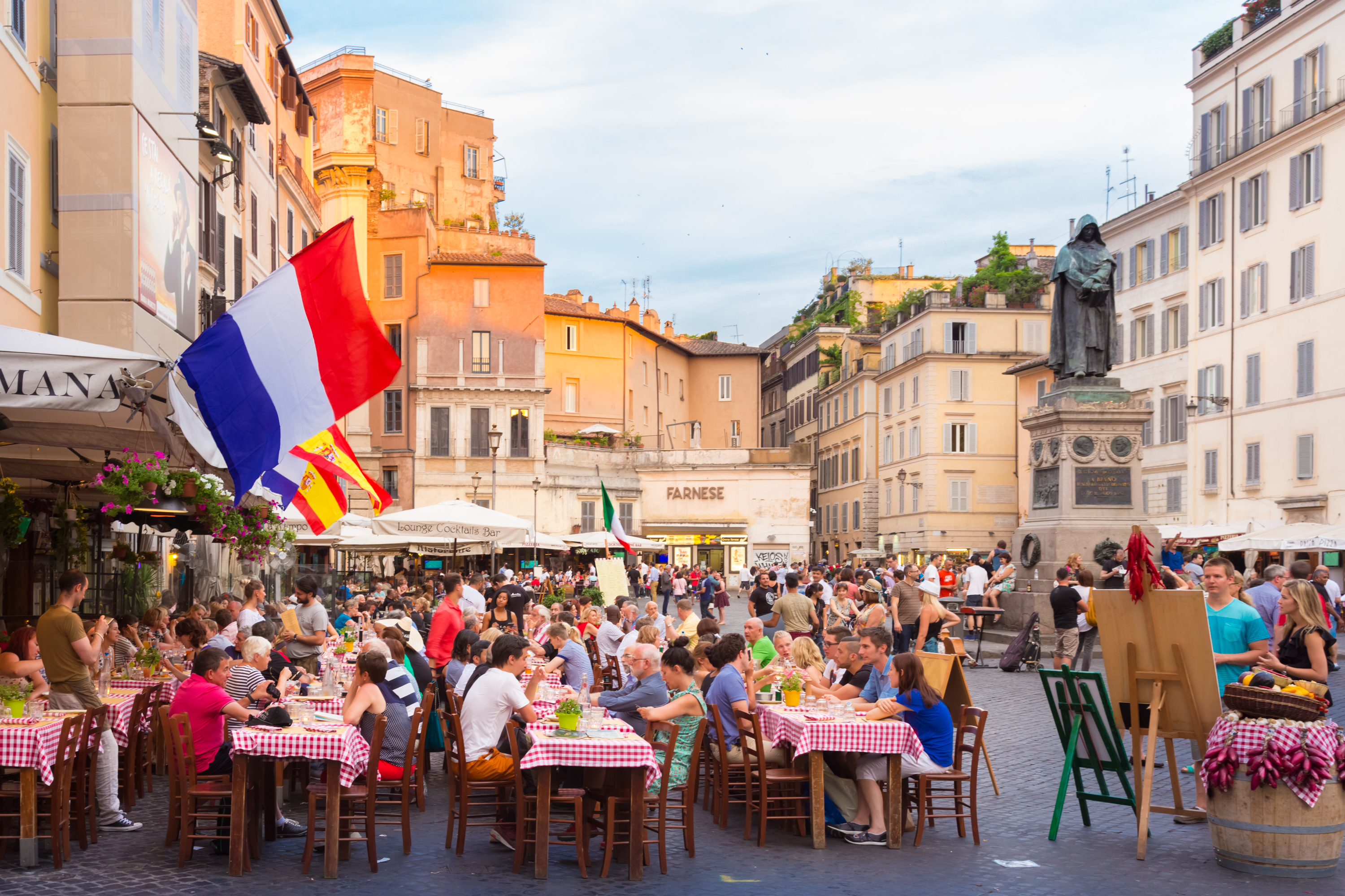 People sit at outside tables in a city square